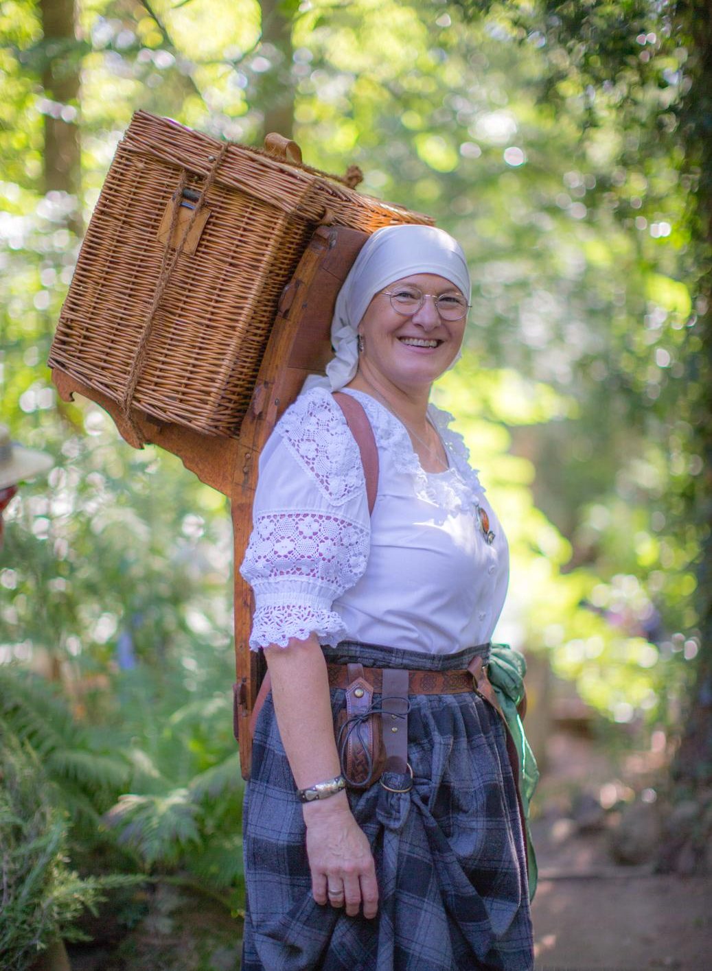 Frau im Kostüm mit einem Weidenkorb auf einem Holzreff